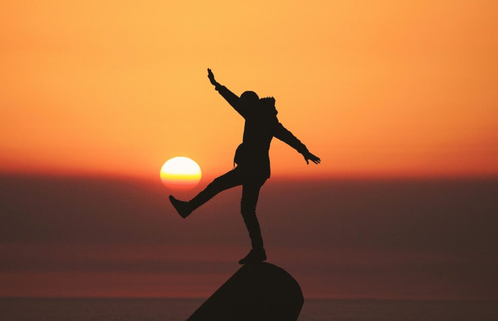A person balancing on a rock, illustrating the topic of how to balance consumption of cannabis and keeping THC tolerance low.